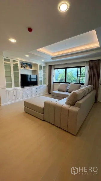 公寓 出租在Watthana, Bangkok - 客厅另一视角，电视柜内置、氛围灯槽与大型窗户，采光充足。