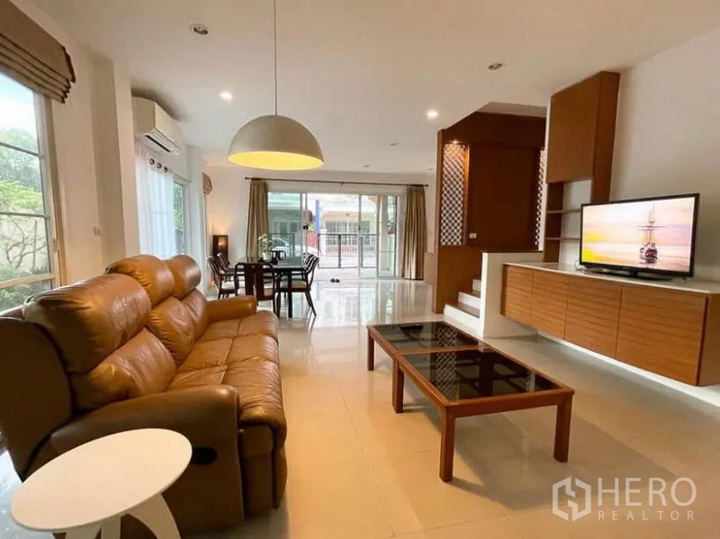 Townhouse for rent in Phasi Charoen, Bangkok - Bright open-plan living and dining area with leather sofa, TV unit and sliding doors.