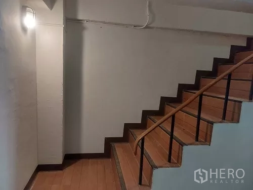Shophouse for rent in Bang Rak, Bangkok - Internal staircase with wooden steps, metal handrail and wall light.