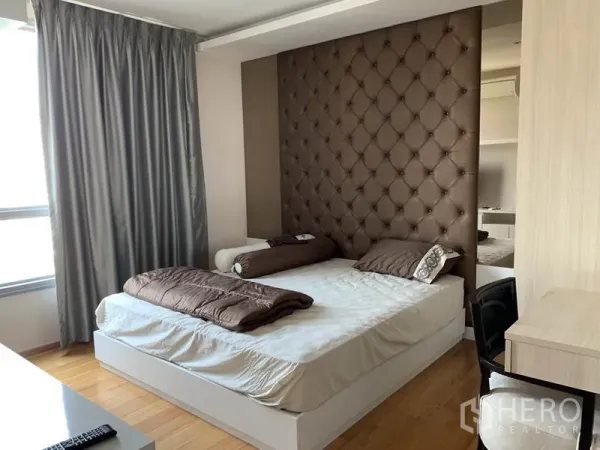 คอนโด ให้เช่าในWatthana, Bangkok - ห้องนอนใหญ่ผนังหัวเตียงบุหนัง เตียงขนาดใหญ่ โต๊ะทำงาน และผ้าม่านเต็มบาน