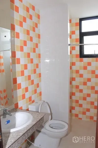 Townhouse for rent in Phaya Thai, Bangkok - Bathroom with orange and beige mosaic wall tiles, a vanity with granite countertop, large mirror, and window.