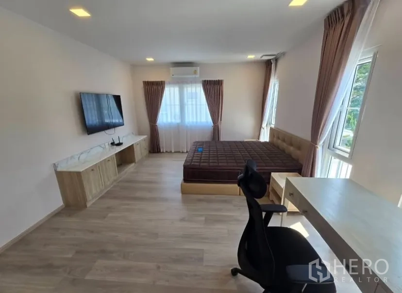 Detached House for rent in Bang Phli, Samut Prakan - Spacious master bedroom with bed, desk, wall‑mounted TV and multiple windows.