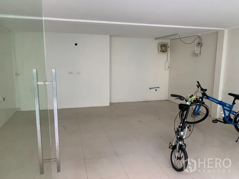 零售空间 出租在Watthana, Bangkok - 室内开放空间，白色瓷砖地面、玻璃门把、素色墙面与基础线路。