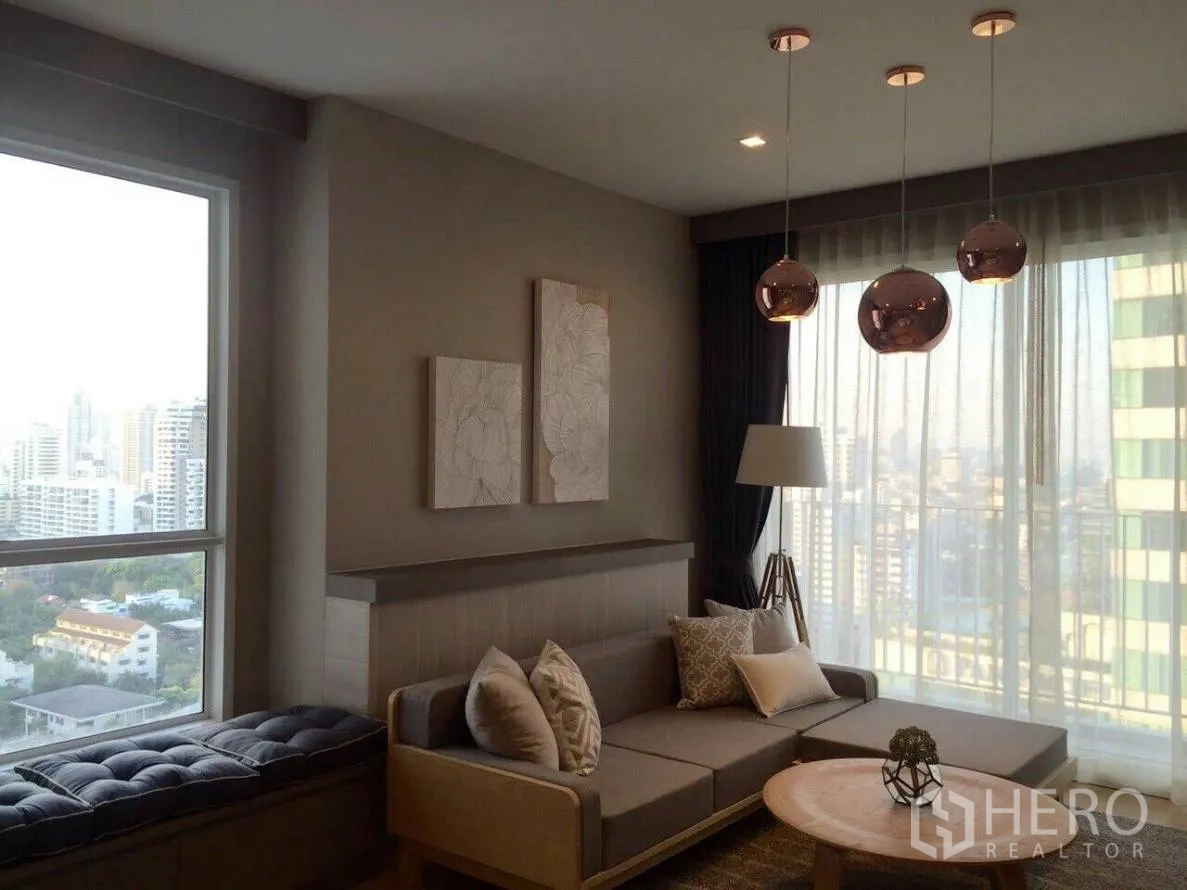 คอนโด ให้เช่าในWatthana, Bangkok - มุมห้องนั่งเล่นพร้อมม้านั่งริมหน้าต่าง โซฟา โต๊ะกลาง และวิวสกายไลน์ผ่านผ้าม่านโปร่ง