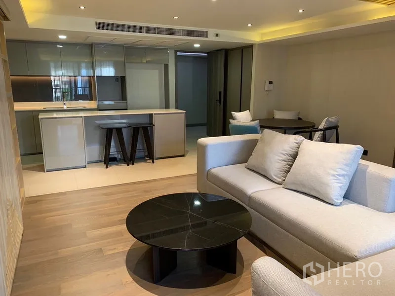 คอนโด ให้เช่าในPathum Wan, Bangkok - ห้องนั่งเล่นร่วมสมัย โต๊ะกลมสีดำ ติดกับครัวบิวท์อินมีไอส์แลนด์และสตูลบาร์