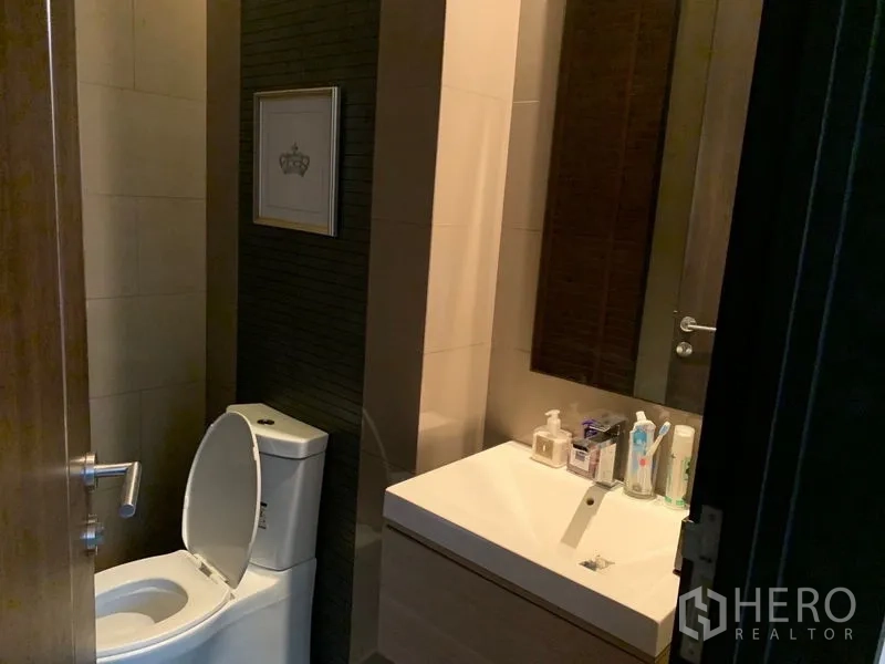 Townhouse for sale in Watthana, Bangkok - Guest bathroom with toilet, sleek vanity and wall mirror.