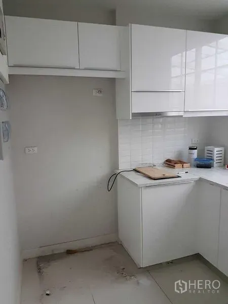 联排别墅 出租在Bang Na, Bangkok - 白色L形厨房，亮面橱柜、贴砖防溅板与吊柜储物。