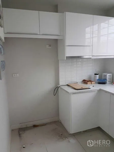 联排别墅 出租在Bang Na, Bangkok - 白色L形厨房，亮面橱柜、贴砖防溅板与吊柜储物。