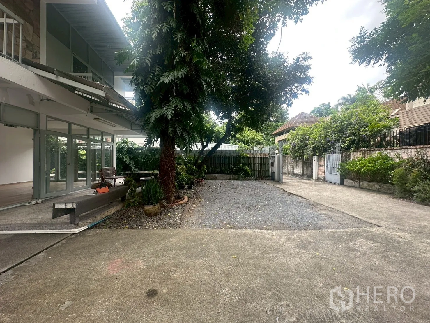 บ้าน ให้เช่าในWatthana, Bangkok - สวนหน้าบ้านมีต้นไม้ใหญ่ พื้นกรวด และทางรถเข้าถึงประตู.