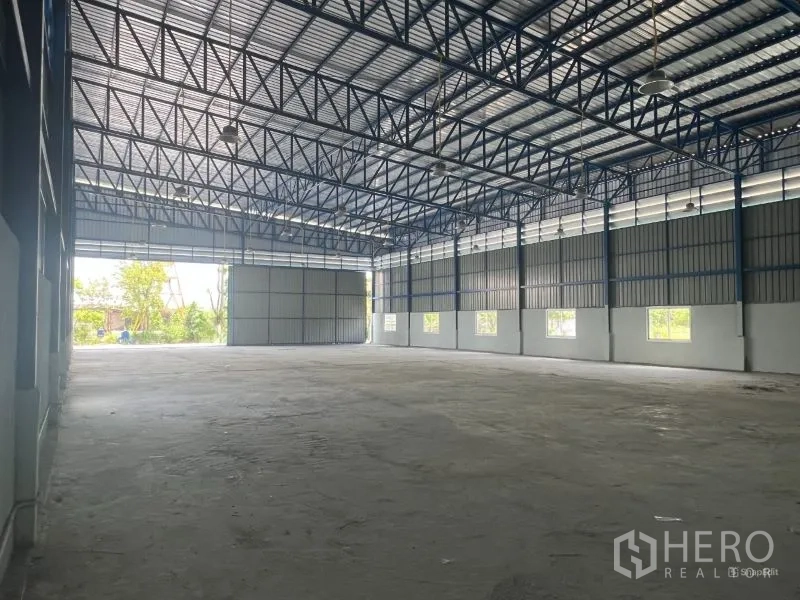 Warehouse for rent in Min Buri, Bangkok - Interior corner featuring built-in restrooms and a utility area beneath the high ceiling.