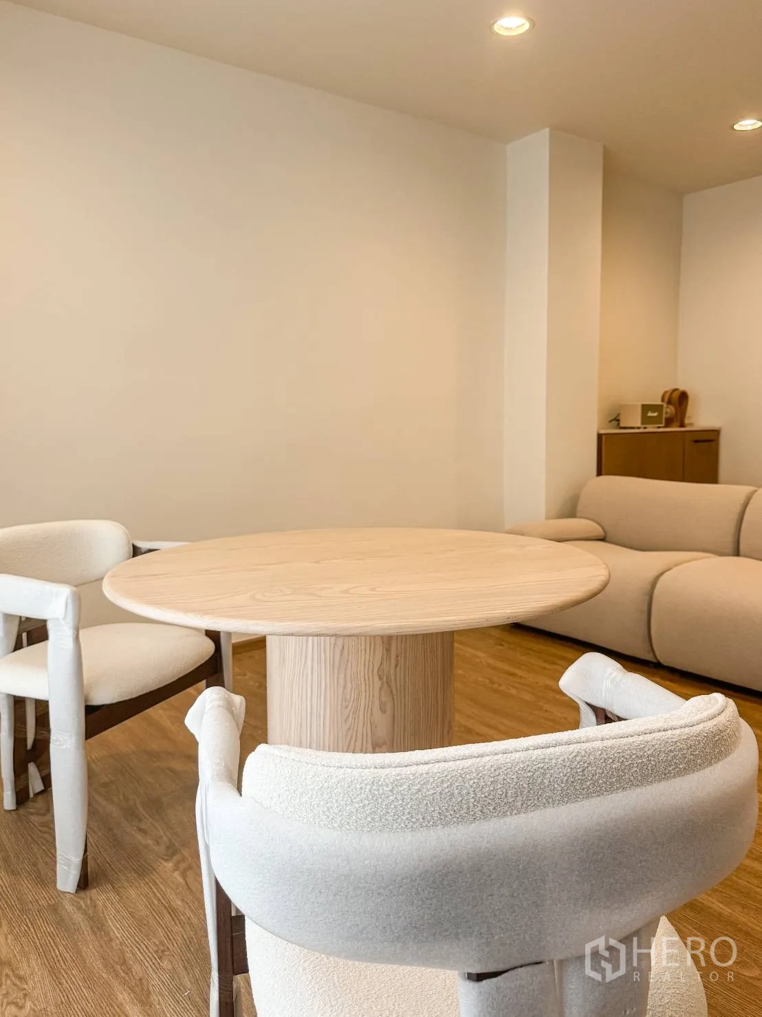 Shophouse for sale in Watthana, Bangkok - Close-up of wooden round table with upholstered chairs beside a beige sofa.