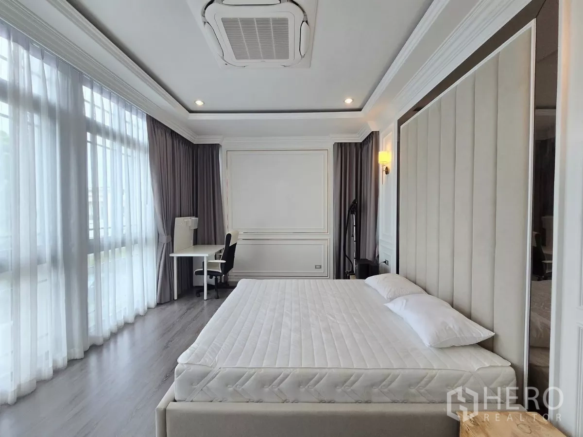 Detached House for rent in Prawet, Bangkok - Primary bedroom with work desk by the window and layered gray drapes.