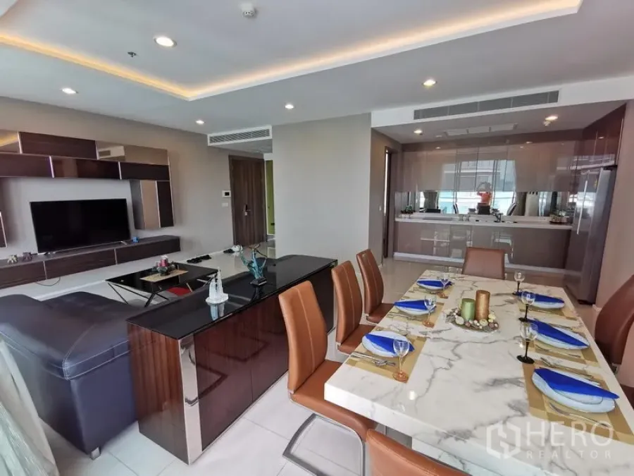 Condominium for rent in Bang Kho Laem, Bangkok - Open-plan living and dining area with a marble table, leather chairs, TV wall and modern lighting.