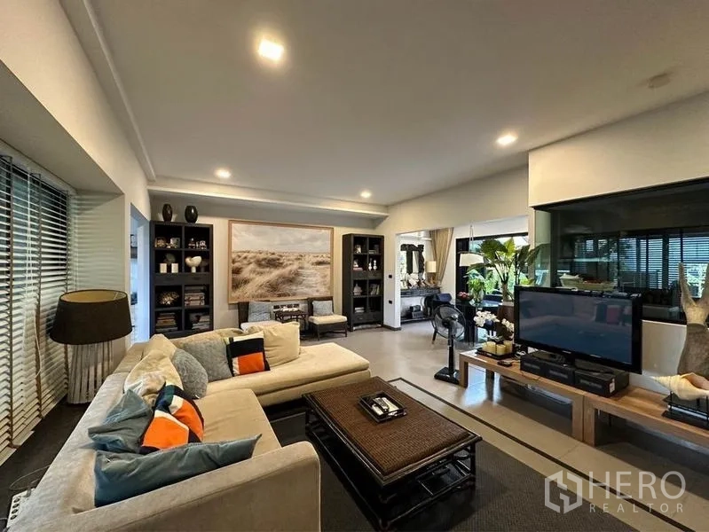 Townhouse for rent or sale in Bang Phli, Samut Prakan - Spacious living room with L-shaped sofa, TV console, recessed lighting and large windows.
