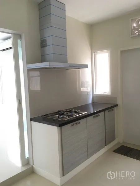 Detached House for rent or sale in Bang Na, Bangkok - Compact kitchen with gas hob, chimney hood and a narrow window for natural light.