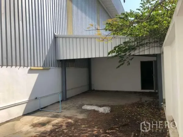 Factory for rent or sale in Bang Phli, Samut Prakan - Covered side yard with metal awning beside the factory, suitable for loading or storage.