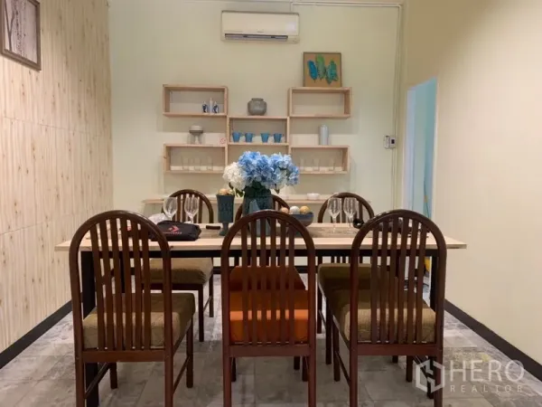 Home Office for rent in Suan Luang, Bangkok - Dining room with long wooden table, eight chairs and wall-mounted shelves.