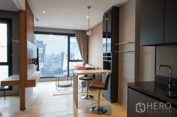 คอนโด ให้เช่าในDin Daeng, Bangkok - ครัวขนาดกะทัดรัดตู้สีเข้ม อ่างล้างจาน และโต๊ะบาร์ที่หันเข้าหาพื้นที่นั่งเล่นกับหน้าต่างบานใหญ่