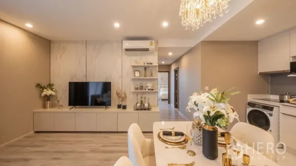 Condominium for rent in Bang Na, Bangkok - Marble-accent TV wall with built-in shelving beside a set dining table and compact kitchen with washer.