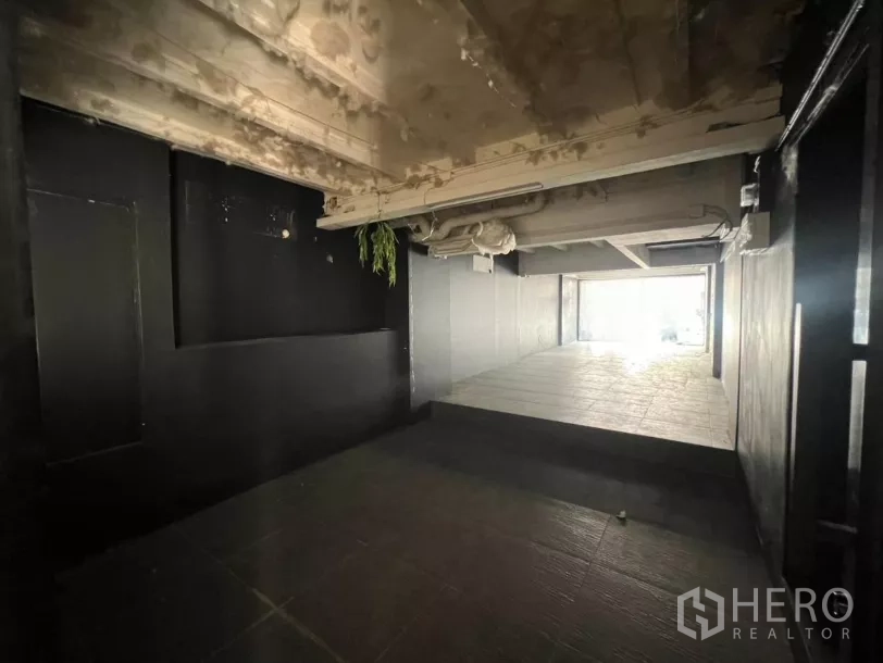 零售空间 出租在Watthana, Bangkok - 室内开间带坡度的瓷砖地面，外露管线与深色墙面。