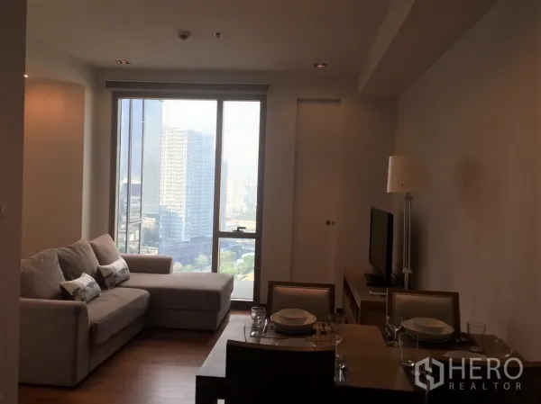 公寓 出租在Khlong Toei, Bangkok - 明亮的客餐厅，沙发与电视，落地窗俯瞰曼谷天际线。