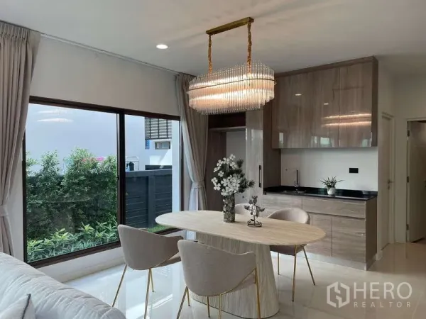 Detached House for rent in Bang Kapi, Bangkok - Dining corner with statement chandelier beside pantry cabinets and sliding glass doors.