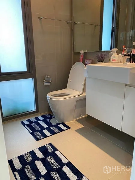 Condominium for sale in Bang Kho Laem, Bangkok - Clean bathroom with frosted window, white vanity and floor tiles.