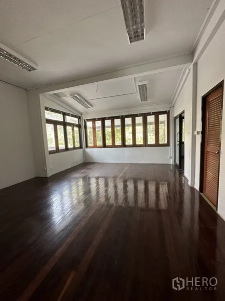 Detached House for rent in Phaya Thai, Bangkok - Spacious upper-floor room with rows of wood-framed windows and glossy timber floor.