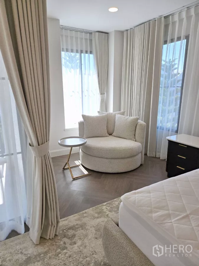 Detached House for rent in Saphan Sung, Bangkok - Bedroom corner with round lounge chair, side table and sheer curtains.