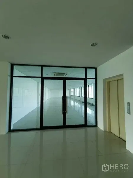 Office Space for rent - Glass double-door entry to a bright office suite beside the elevator lobby with tiled floors and black aluminum frames.