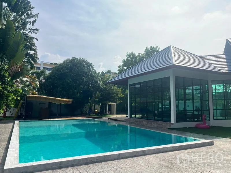 Detached House for sale in Prawet, Bangkok - Swimming pool facing a glass-walled pavilion and landscaped garden.