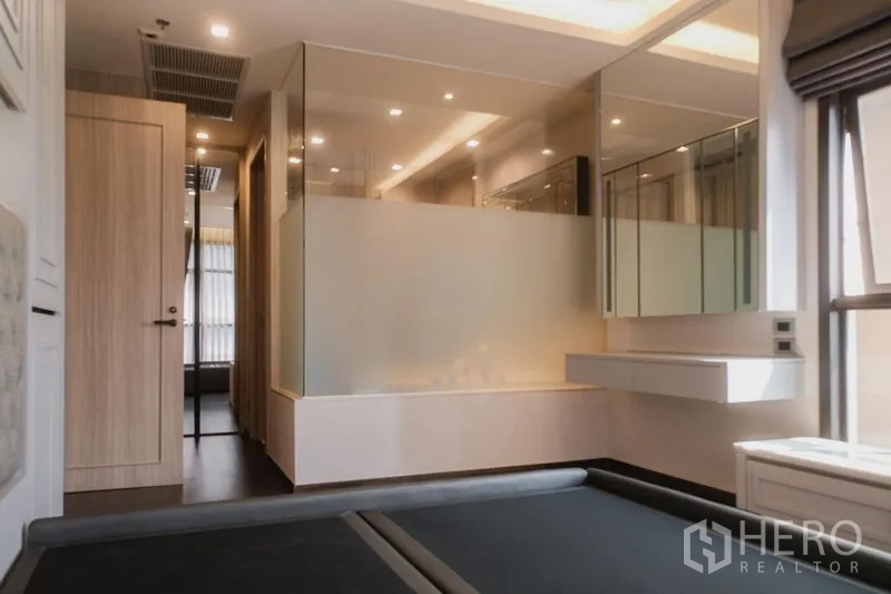 Condominium for rent or sale in Watthana, Bangkok - Master suite with glass‑partition bathroom, soaking tub and mirrored cabinets.