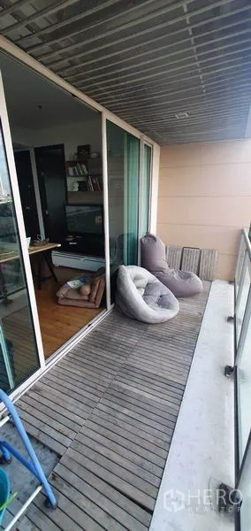 Condominium for rent in Yan Nawa, Bangkok - Covered balcony with wooden decking and beanbag seating.