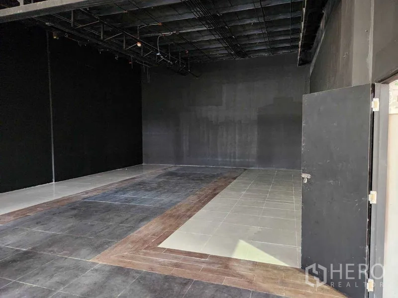 พื้นที่ขายปลีก ให้เช่าในKhlong Toei, Bangkok - ภายในร้านว่าง พื้นกระเบื้องหลายโทน ผนังสีดำ และเพดานโชว์งานระบบ พร้อมตกแต่งได้ทันที