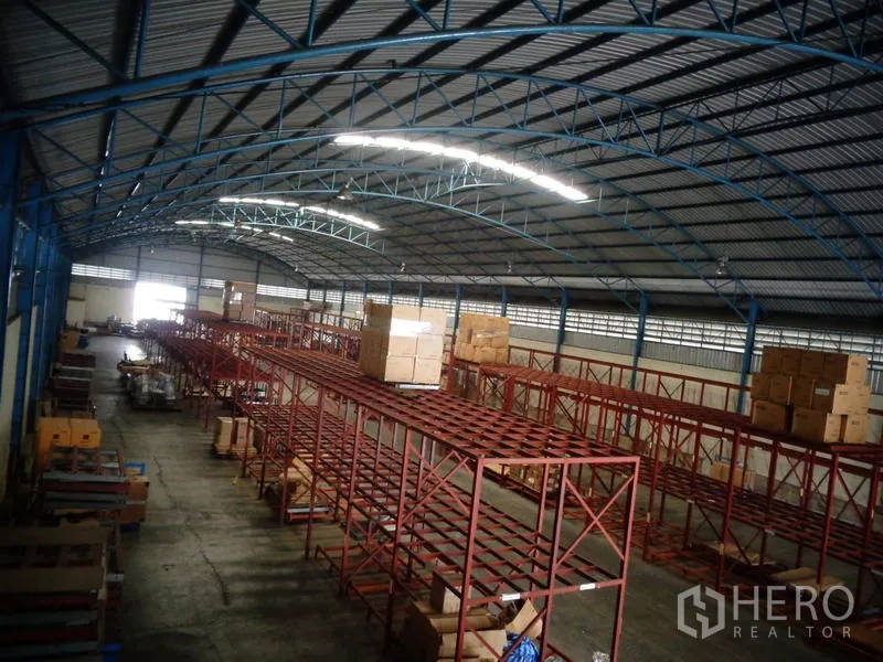 Warehouse for rent or sale in Lat Lum Kaeo, Pathum Thani - Deep aisle perspective highlighting continuous pallet racking and bright strip lighting.