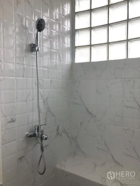 Condominium for rent in Watthana, Bangkok - Bathroom shower with handheld showerhead, white and marble-look tiles and glass-block window.