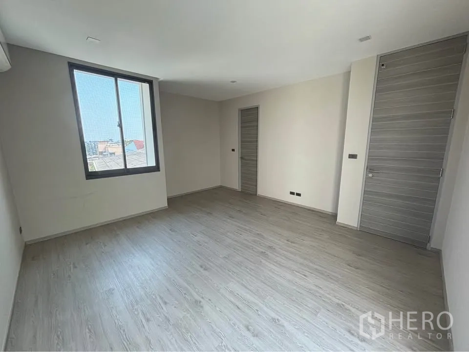 Home Office for rent or sale in Suan Luang, Bangkok - Spacious room with large window, light wood flooring, and neutral walls.