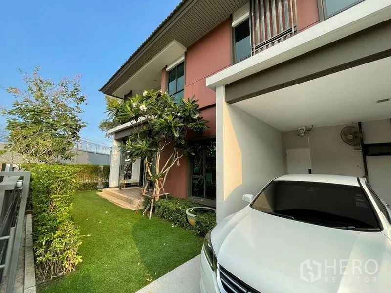 独立式住宅 出售在Pak Kret, Nonthaburi - 两层住宅外观，带遮雨车棚与整洁的前庭。