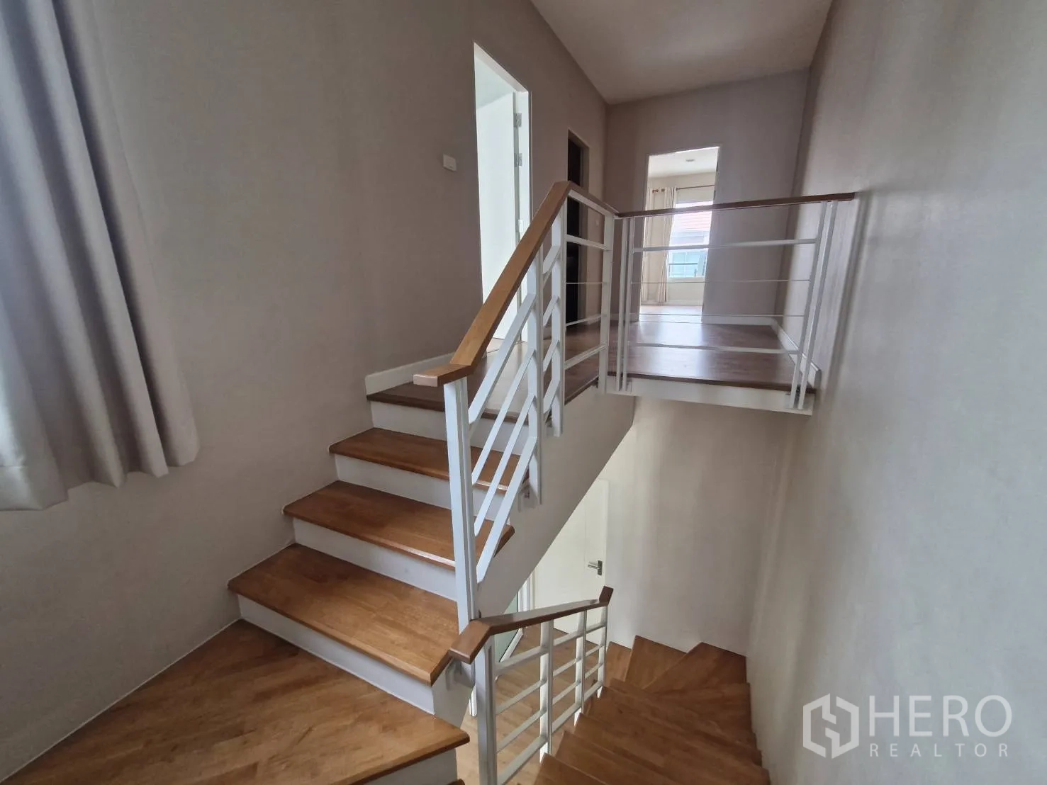 Townhouse for sale in Rat Burana, Bangkok - Wooden staircase and landing with white handrails leading to the upper floor.