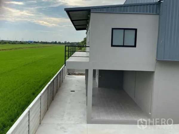 Warehouse for rent or sale in Bang Len, Nakhon Pathom - Rear balcony and covered section of the warehouse overlooking green rice fields.