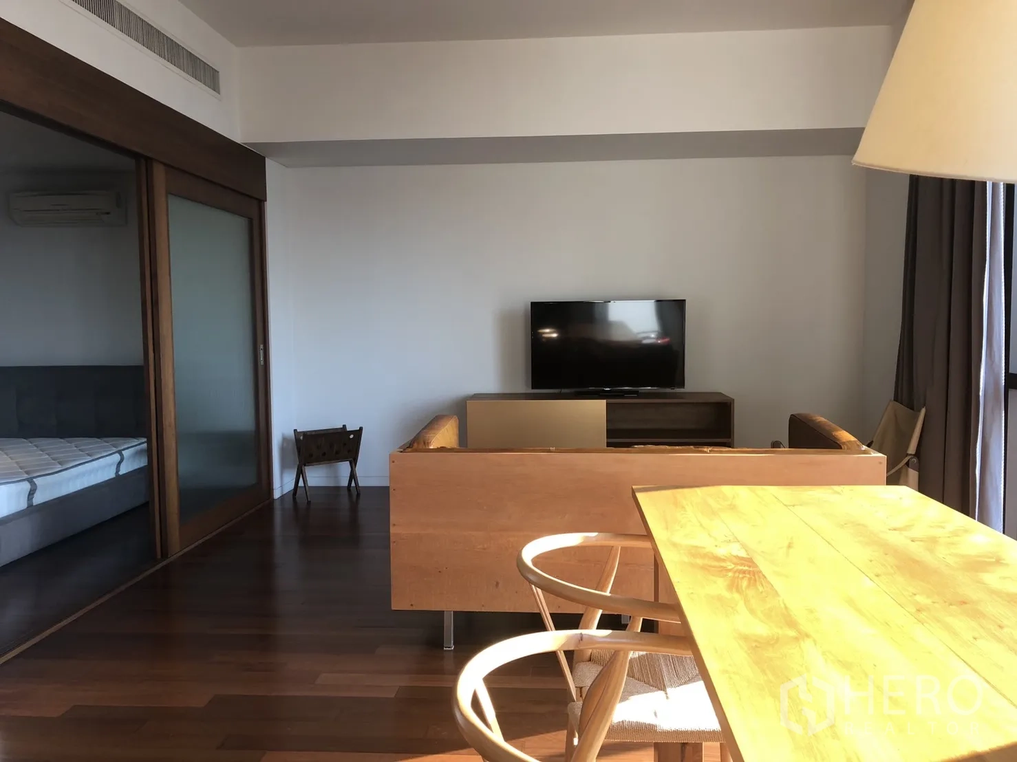 公寓 出租在Pathum Wan, Bangkok - 客厅朝向电视，配木质餐桌椅，推拉门连接卧室