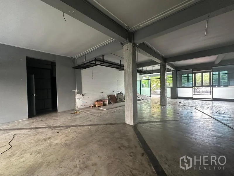 พื้นที่ขายปลีก ให้เช่า - เลเอาต์โล่ง มีผนังอิฐสีขาว ชั้นแขวนโลหะ และประตูกระจกบานใหญ่