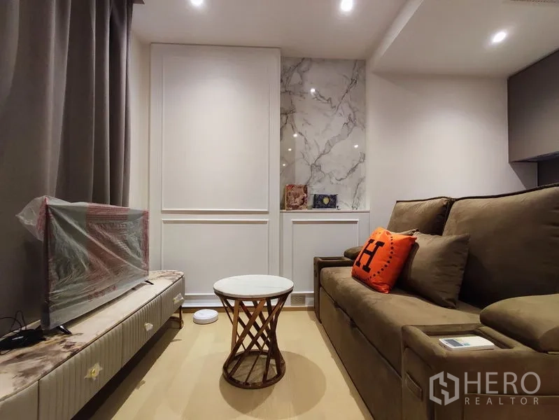 คอนโด ให้เช่าในDin Daeng, Bangkok - พื้นที่นั่งเล่นขนาดเล็ก โซฟานุ่มหันเข้าหาชั้นวางทีวีและผนังตกแต่งหินอ่อน