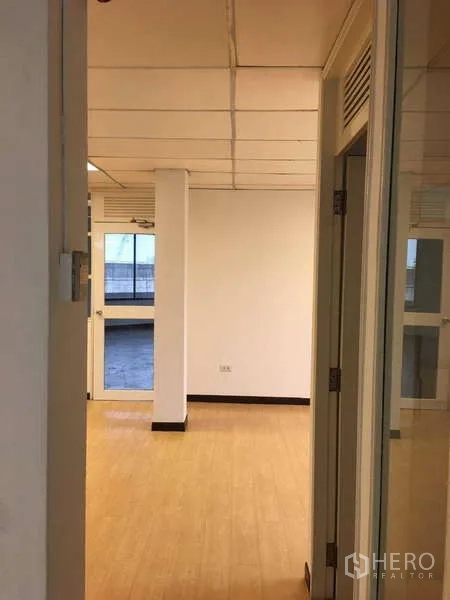 Office Space for rent in Bang Na, Bangkok - Entrance corridor leading to bright office with wood-look floors and glass door.