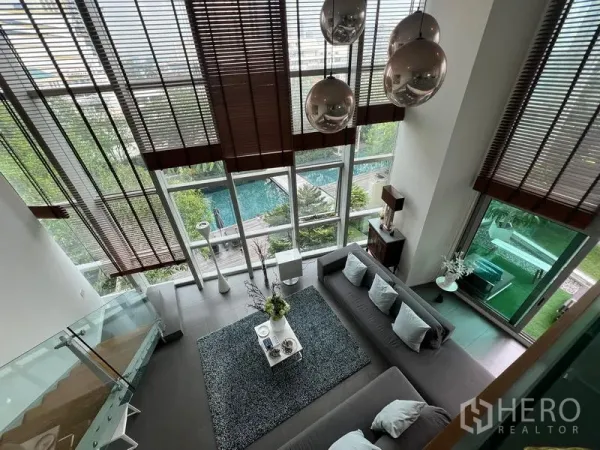 คอนโด ขายในKhlong San, Bangkok - มุมมองจากชั้นลอยลงสู่ห้องนั่งเล่น ผนังกระจกเต็มความสูงและวิวสระว่ายน้ำ