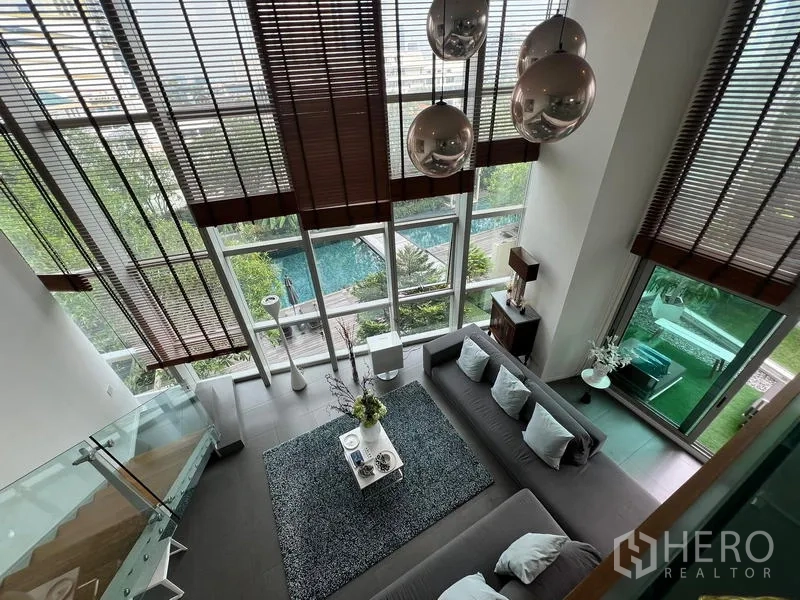 คอนโด ขายในKhlong San, Bangkok - มุมมองจากชั้นลอยลงสู่ห้องนั่งเล่น ผนังกระจกเต็มความสูงและวิวสระว่ายน้ำ