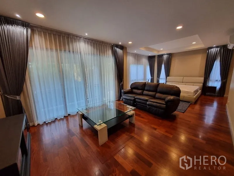 Detached House for rent in Bang Khae, Bangkok - Expansive master suite with seating area, glass coffee table, and wood floors.