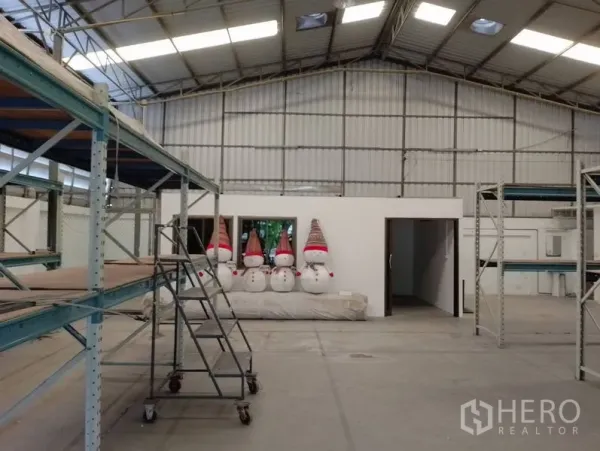 Warehouse for rent in Huai Khwang, Bangkok - High-ceiling warehouse interior with metal roof, concrete floor, small office room and heavy-duty racks.