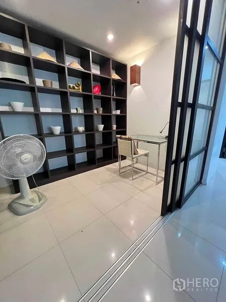 Condominium for rent in Ratchathewi, Bangkok - Home office corner with a glass desk and full‑height built‑in shelving.