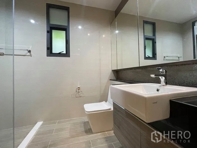 Detached House for rent in Bang Na, Bangkok - Minimalist bathroom with large mirror, square basin and side window.
